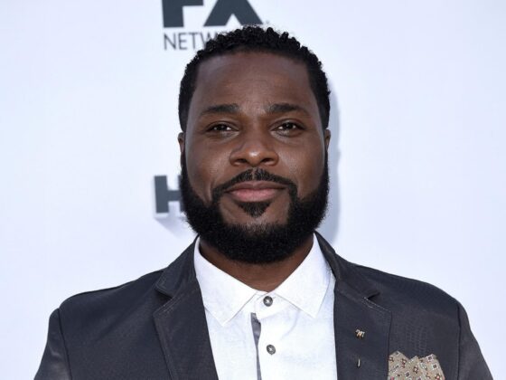 Portrait of Malcolm-Jamal Warner smiling warmly in a suit, honoring his legacy after his passing in July 2025.