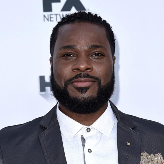 Portrait of Malcolm-Jamal Warner smiling warmly in a suit, honoring his legacy after his passing in July 2025.