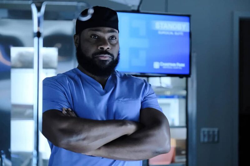 Malcolm-Jamal Warner in character as Dr. AJ Austin from The Resident, wearing scrubs